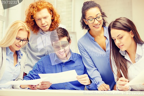 Image of smiling team with paper at office