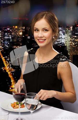 Image of smiling young woman eating main course