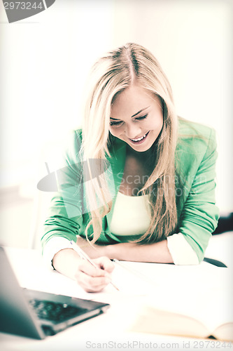 Image of smiling student girl writing in notebook