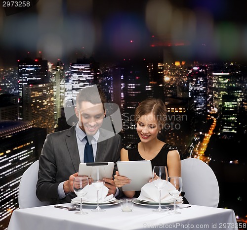 Image of couple with menus on tablet pc at restaurant