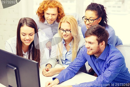 Image of smiling business team looking at computer monitor