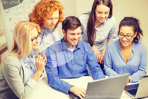 Image of smiling team with laptop computers in office
