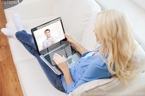 Image of smiling woman with laptop computer at home