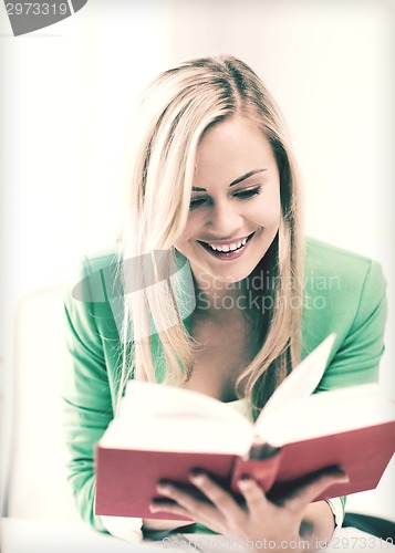 Image of smiling young woman reading book at school