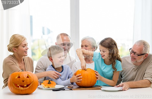 Image of happy family sitting with pumpkins at home