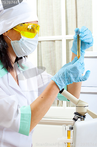 Image of doctor looking at a test tube of yellow solution