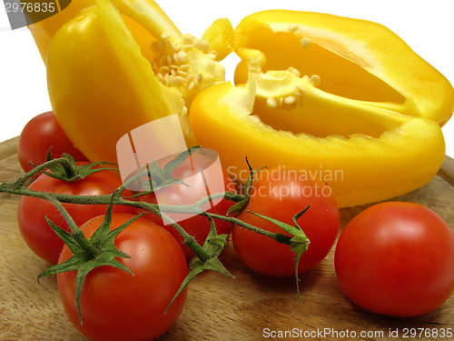 Image of Halved yellow pepper and tomatoes on wooden plate  with knife