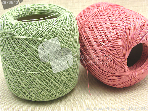 Image of Two balls of wool  in green and pink on background