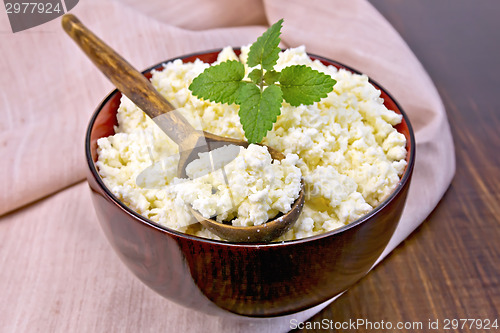 Image of Curd in wooden bowl with spoon and mint on board