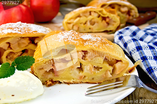 Image of Strudel with apples in bowl with ice cream on board