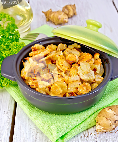 Image of Jerusalem artichokes roasted in pan with oil on light board