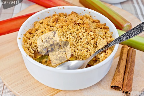 Image of Crumble with rhubarb in bowl on linen tablecloth and board