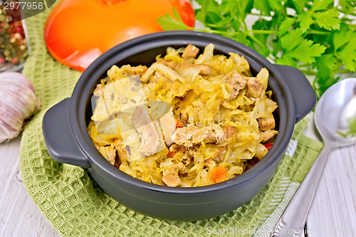 Image of Cabbage stew with meat in black pot on napkin