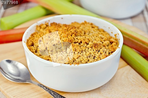 Image of Crumble with rhubarb in bowl on tablecloth and board
