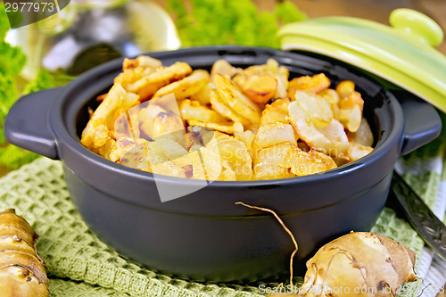 Image of Jerusalem artichokes roasted in pan with lid on board