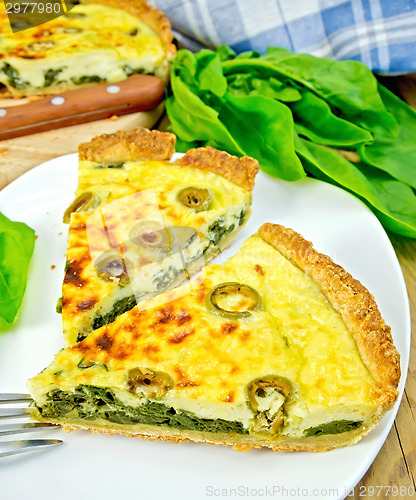 Image of Pie with spinach and olives in plate on board