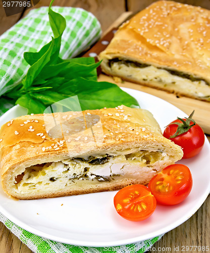 Image of Roll filled with spinach and cheese on board with tomatoes