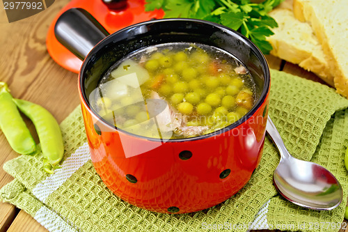 Image of Soup from green peas with meat in red bowl on napkin