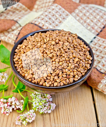 Image of Buckwheat in brown bowl with flower on board