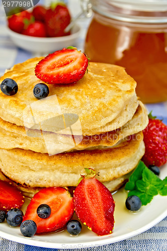 Image of Flapjacks with strawberries and blueberries on linen tablecloth
