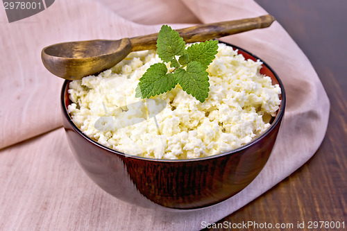 Image of Curd in wooden bowl with spoon and mint on napkin