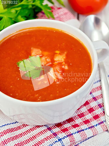 Image of Soup tomato with parsley on napkin and spoon