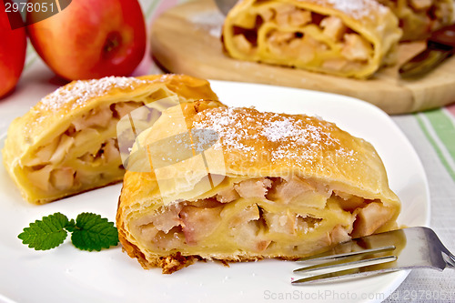 Image of Strudel with apples in bowl on linen tablecloth