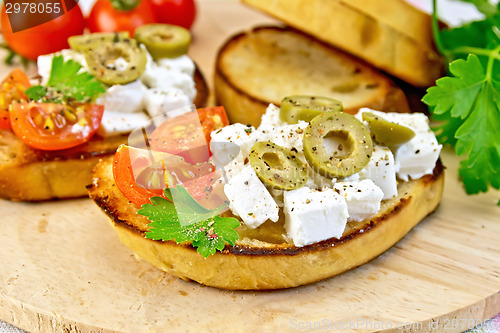 Image of Sandwich with feta and olives on wooden board