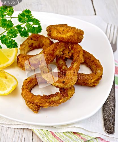 Image of Calamari fried with lemon and fork on plate and napkin