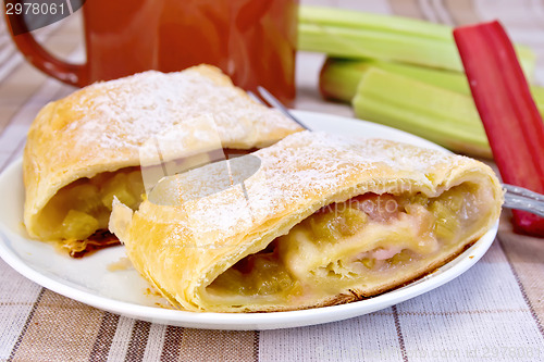 Image of Strudel with rhubarb and mug on linen tablecloth