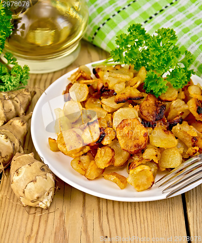 Image of Jerusalem artichokes fried in dish with napkin on board