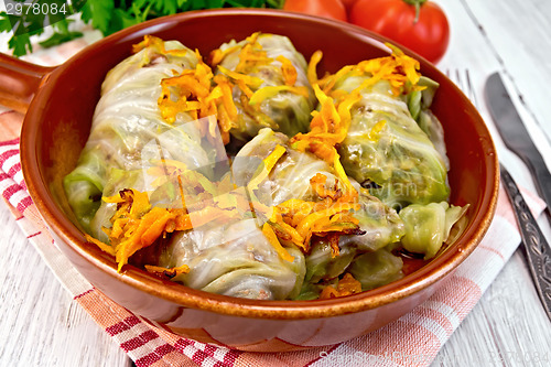 Image of Cabbage stuffed with sauerkraut in ceramic pan on board