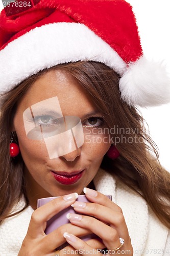 Image of Cold young woman in a Santa hat sipping coffee tea