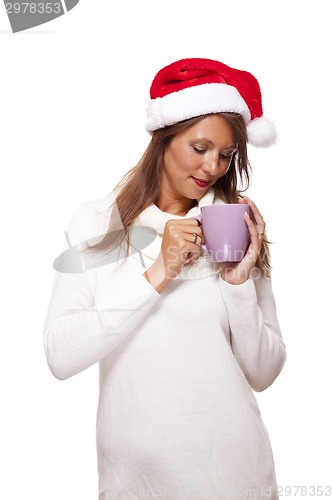 Image of Cold young woman in a Santa hat sipping coffee tea