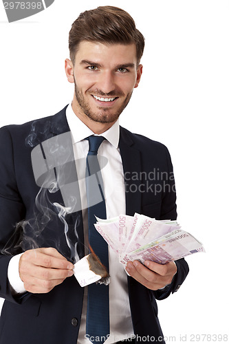 Image of Wealthy successful businessman burning money