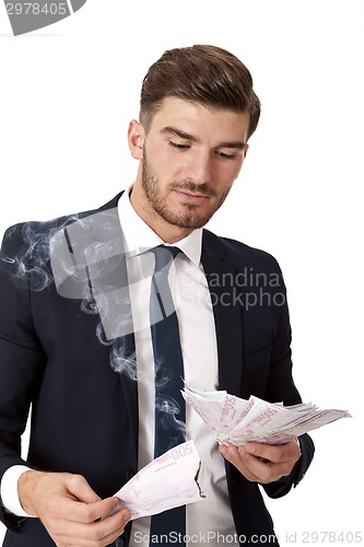 Image of Wealthy successful businessman burning money