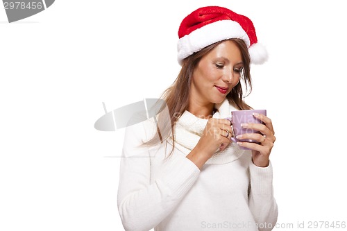 Image of Cold young woman in a Santa hat sipping coffee tea