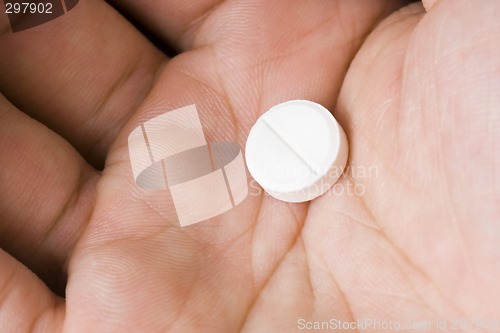 Image of Single white pill in palm

