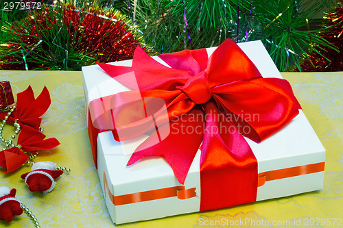 Image of Beautifully packed gift by Christmas and the decorated fir-tree.