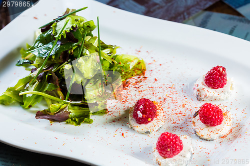 Image of fresh salad with goat cheese and raspberry.