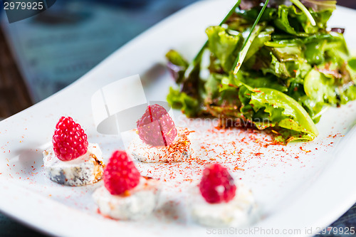 Image of fresh salad with goat cheese and raspberry.