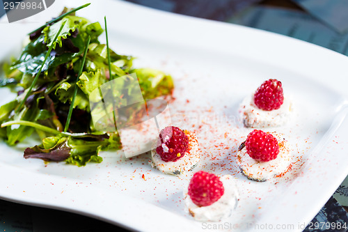 Image of fresh salad with goat cheese and raspberry.