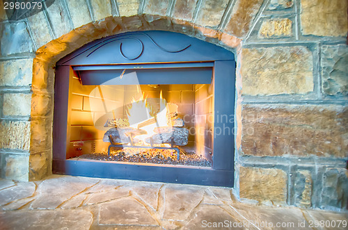 Image of luxurious stone structure fireplace with burning fire