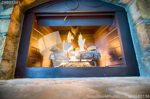 Image of luxurious stone structure fireplace with burning fire