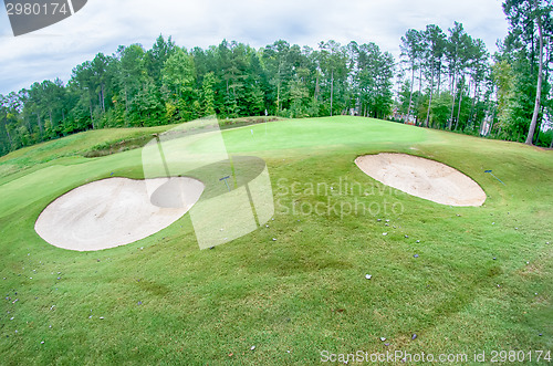 Image of green grass of the golf course surrounded by autumnal forest