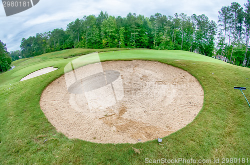 Image of green grass of the golf course surrounded by autumnal forest
