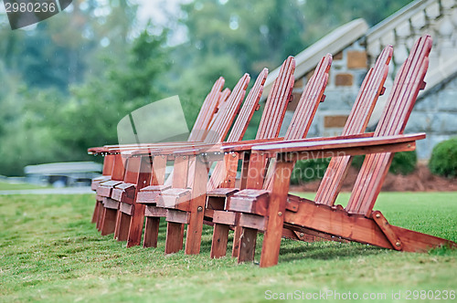 Image of Two wooden adirondack chairs on lush green lawn