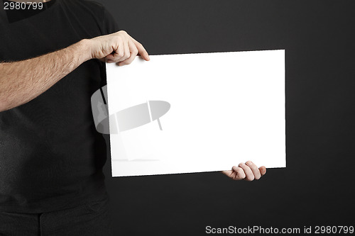 Image of Man in black clothes holds poster