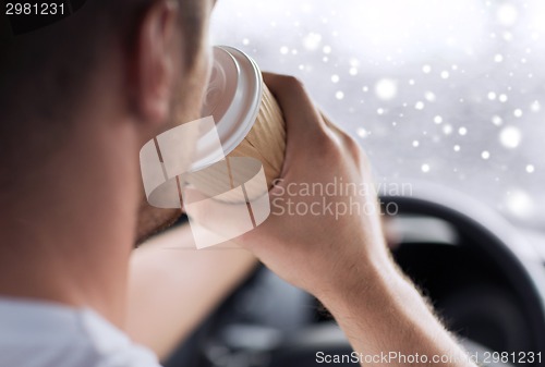 Image of close up of man drinking coffee while driving car