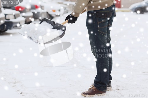 Image of closeup of man digging snow with shovel near car